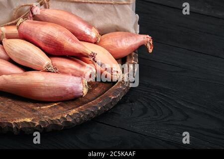 Zwiebelschalotte auf schwarzem, dunklem Hintergrund. Essen Gemüse und gesund essen. Essen Schalotten, Zugabe zu verschiedenen Gerichten, diversifizieren Lebensmittel. Stockfoto