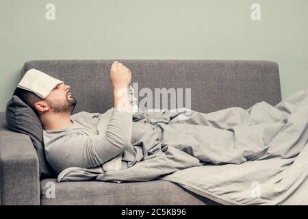 Krankheit. Zu Hause erfreuen. Ein junger Mann ist krank, ist zu Hause behandelt. Bläst ihre Nase in eine Serviette, laufende Nase. Infektion, Epidemie, Bacillus Träger. Stockfoto