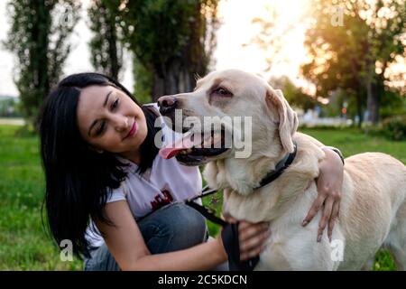 Schöne junge Frau genießen Zeit mit ihrem besten Freund Labrador Hund im Park. Freizeitaktivitäten im Freien mit einem Haustier. Stockfoto