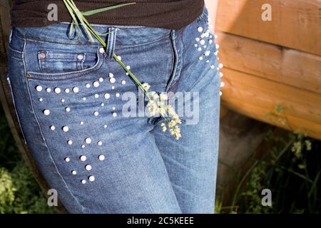 Ein Bündel von grünem Gras auf dem Hintergrund eines Mädchens in Jeans. Nahaufnahme. Stockfoto