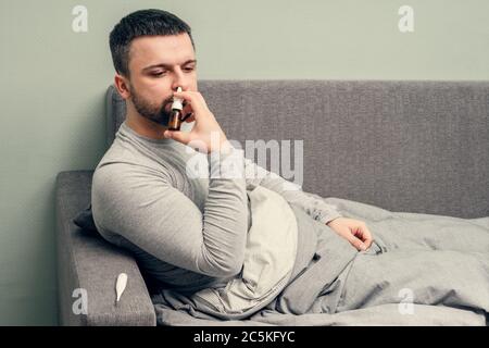 Krankheit. Zu Hause erfreuen. Ein junger Mann ist krank, ist zu Hause behandelt. Bläst ihre Nase in eine Serviette, laufende Nase. Infektion, Epidemie, Bacillus Träger. Stockfoto