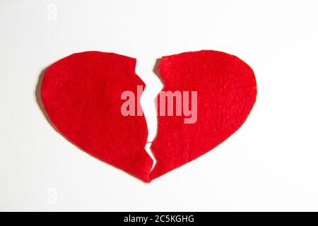 Gebrochenes rotes Herz aus Filz. Kaputtes Liebeskonzept. Ein gebrochenes Herz auf weißem Hintergrund isoliert. Ein Schmerz in meinem Herzen Stockfoto