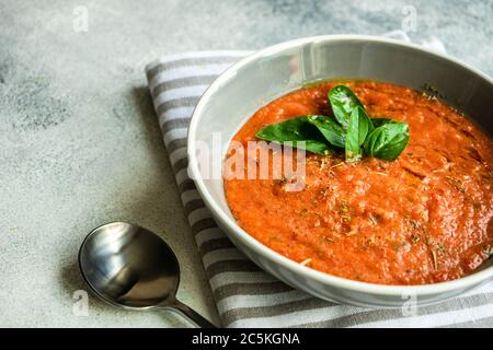 Traditionelle spanische Tomatensuppe Gazpacho serviert in einer Keramikschale mit frischen Basilikumblättern auf Steingrund mit Platz zum Kopieren Stockfoto