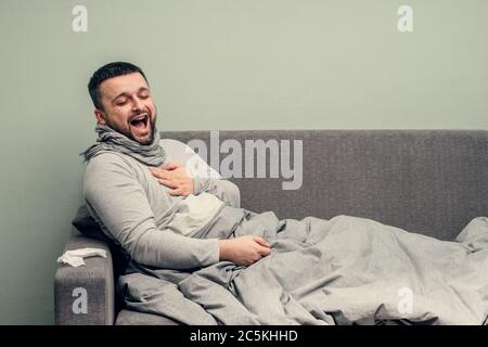Krankheit. Zu Hause erfreuen. Ein junger Mann ist krank, ist zu Hause behandelt. Bläst ihre Nase in eine Serviette, laufende Nase. Infektion, Epidemie, Bacillus Träger. Stockfoto