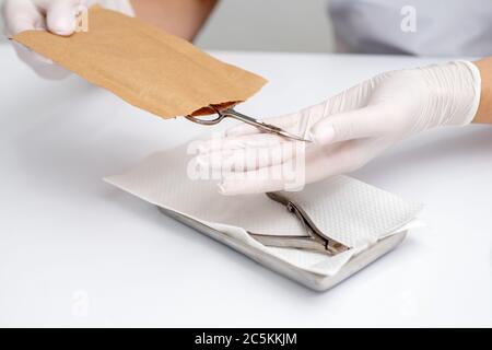 Manikuristen Hände nehmen Maniküre Werkzeuge aus Handwerk Umschlag vor Maniküre Verfahren durch den weißen Tisch Stockfoto