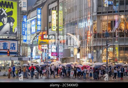 Menschenmenge, die darauf warten, die berühmte Shibuya Scramble Kreuzung in einer regnerischen Nacht zu überqueren, Tokio, Japan. Stockfoto