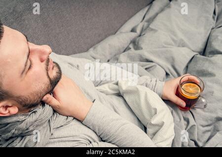 Krankheit. Zu Hause erfreuen. Ein junger Mann ist krank, ist zu Hause behandelt. Bläst ihre Nase in eine Serviette, laufende Nase. Infektion, Epidemie, Bacillus Träger. Stockfoto