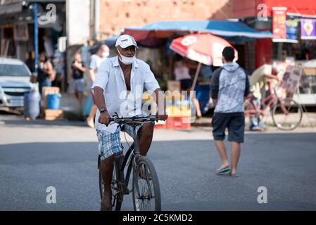 Rio de Janeiro, Brasilien - 3. Juli 2020: Die Menschen tragen Gesichtsmasken. Älterer Mann auf dem Fahrrad auf der Straße. Stockfoto
