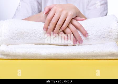Schöne Hände von jungen Frau Nahaufnahme auf Handtuch. Spa-Behandlungen für Nägel. Leerzeichen für Text. Frau hält Hände auf Handtuch für die Maniküre Behandlung proceur Stockfoto