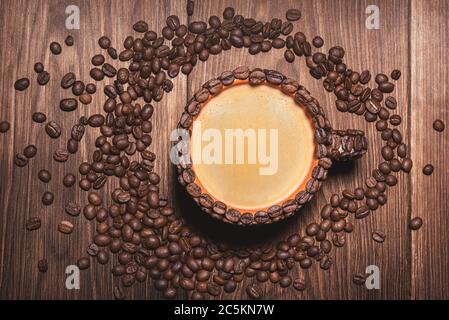 Kaffeetasse mit Kaffee aus Kaffeebohnen Holztisch. Hintergrund für Kaffeebohnen in dunklen Farben für das Telefon. Stockfoto