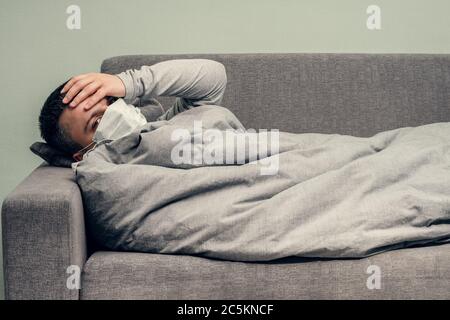 Krankheit. Zu Hause erfreuen. Ein junger Mann ist krank, ist zu Hause behandelt. Bläst ihre Nase in eine Serviette, laufende Nase. Infektion, Epidemie, Bacillus Träger. Stockfoto