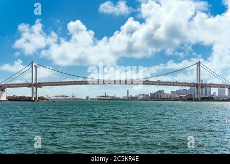 tokio, japan - april 04 2020: Zweischichtige Aufhängung Rainbow Bridge in der Bucht von Tokio mit den Portalkranen des International Container Terminal of Stockfoto