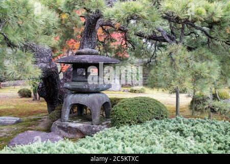 Traditionelle Laterne aus Stein im japanischen Garten des Nijo Castle in Kyoto, die, wenn sie beleuchtet wird, als ein Angebot an Buddha betrachtet. Stockfoto