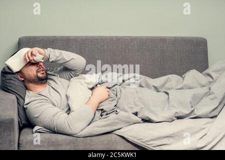 Krankheit. Zu Hause erfreuen. Ein junger Mann ist krank, ist zu Hause behandelt. Bläst ihre Nase in eine Serviette, laufende Nase. Infektion, Epidemie, Bacillus Träger. Stockfoto