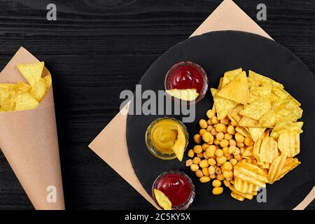 Große Auswahl an Snacks für Bier mit verschiedenen Saucen auf Pergament Draufsicht Stockfoto