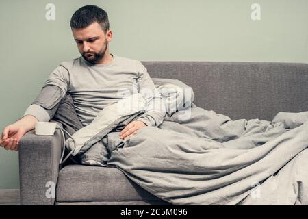 Krankheit. Zu Hause erfreuen. Ein junger Mann ist krank, ist zu Hause behandelt. Bläst ihre Nase in eine Serviette, laufende Nase. Infektion, Epidemie, Bacillus Träger. Stockfoto
