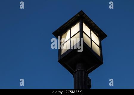 Beleuchtete Vintage Street Lamp. Schwarzer Lampenpfosten mit Kopierraum beleuchtet. Stockfoto