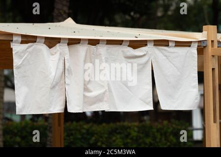 Der Vorhang-ähnliche Stoff, der vor traditionellen japanischen Restaurants und Geschäften hängt, dient nicht nur als Schild, sondern hat eine größere Bedeutung, Stockfoto