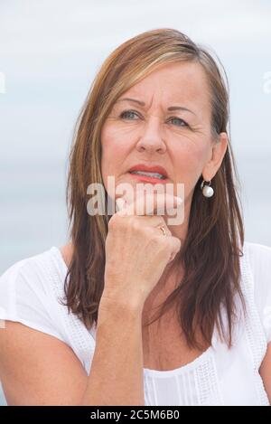 Portrait Attraktive reife Frau, besorgt und besorgt, nachdenklich mit der Hand am Kinn. Stockfoto