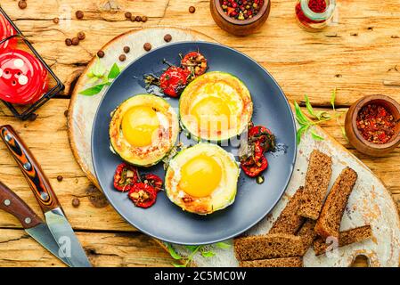 Spiegeleier mit Tomaten und Brot auf dem Teller auf rustikalem Holztisch Stockfoto
