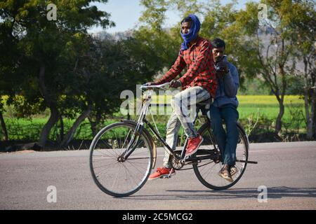 TIKAMGARH, MADHYA PRADESH, INDIEN - 28. JANUAR 2020: Zwei Männer fahren auf dem Fahrrad im Freien. Stockfoto