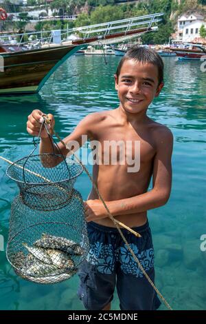 Ein Junge zeigt seinen mit einer Handschnur gefangenen Fischkorb im römischen Hafen der Altstadt von Kaleici in Antalya in der Türkei. Stockfoto