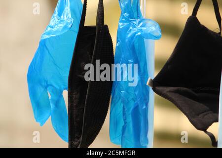 Nahsicht von Staub- und Virenschutzmaske und Handschuhen, die unter Tageslicht zusammenhängen. Stockfoto