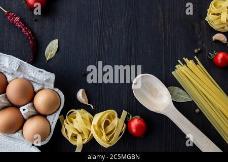 Kochen Lebensmittel Hintergrund mit freiem Platz für Text. Zusammensetzung mit Spaghetti, Tomaten, Eiern, Knoblauch, Lorbeerblatt über dem Holzhintergrund. Zutaten für Stockfoto