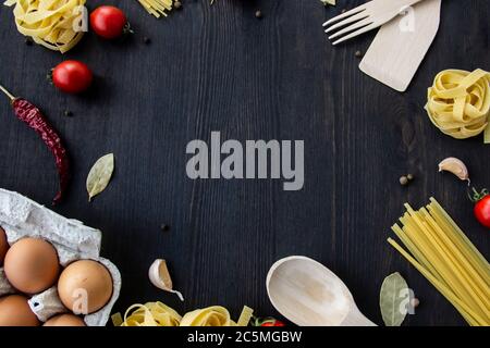Kochen Lebensmittel Hintergrund mit freiem Platz für Text. Zusammensetzung mit Spaghetti, Tomaten, Eiern, Knoblauch, Lorbeerblatt über dem Holzhintergrund. Zutaten für Stockfoto