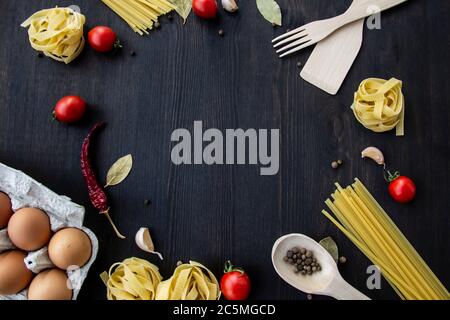 Kochen Lebensmittel Hintergrund mit freiem Platz für Text. Zusammensetzung mit Spaghetti, Tomaten, Eiern, Knoblauch, Lorbeerblatt über dem Holzhintergrund. Zutaten für Stockfoto