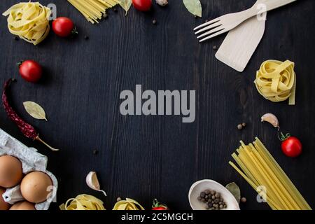 Kochen Lebensmittel Hintergrund mit freiem Platz für Text. Zusammensetzung mit Spaghetti, Tomaten, Eiern, Knoblauch, Lorbeerblatt über dem Holzhintergrund. Zutaten für Stockfoto
