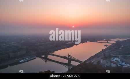 Luftaufnahme der Freiheitsbrücke und der Donau vom Gellert-Hügel bei Sonnenaufgang im Nebel in Budapest, Ungarn Stockfoto