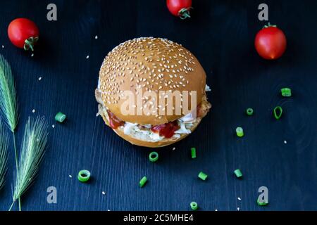 Leckere Burger mit gebratenen Schweinefleischscheiben, Kohl in Sauce, Gurken aus der Dose und Ketchup auf dem Holzhintergrund Stockfoto