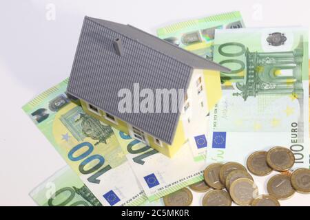 Modellhaus mit (Euro)Banknoten und Münzen als Symbolbild für hohe Immobilienpreise Stockfoto