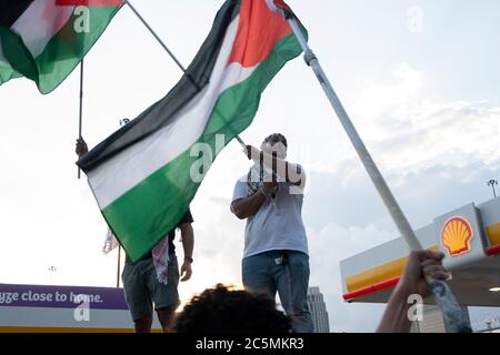 Atlanta, USA. Juli 2020. Demonstranten schwenken Fahnen, während sie auf einem Tankstellenschild stehen, um das Bewusstsein für Ungerechtigkeiten gegen das palästinensische Volk zu verbreiten. Quelle: Micah Casella/Alamy Live News. Stockfoto