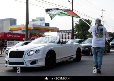 Atlanta, USA. Juli 2020. Ein Protestler tanzt und schwenkt eine Fahne auf Autos, um das Bewusstsein für Ungerechtigkeiten gegen das palästinensische Volk zu verbreiten. Quelle: Micah Casella/Alamy Live News. Stockfoto