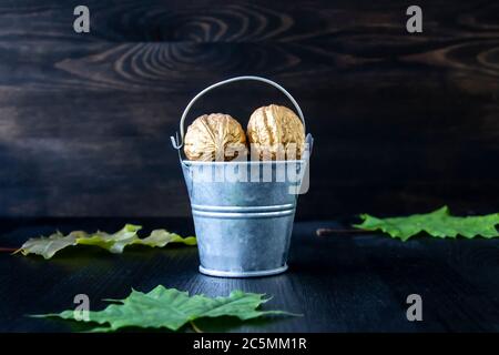 Eimer mit goldenen Walnüssen auf Holzgrund. Konzeptfoto Stockfoto