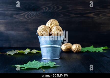 Eimer mit goldenen Walnüssen auf Holzgrund. Konzeptfoto Stockfoto