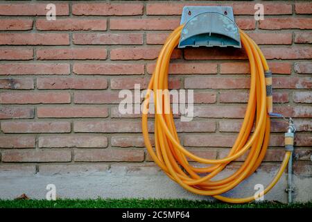 Orange Gartenschlauch an der Wand Stockfoto