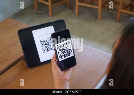 Frauen Hand verwendet eine Handy-Anwendung, um QR-Codes in Geschäften, die digitale Zahlungen ohne Geld und Plastikanhänger auf dem Tisch akzeptieren scannen. QR-C Stockfoto