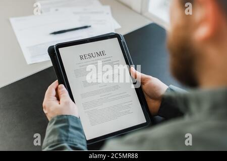 Männliche Arbeitssuchende Überprüfung elektronische Lebenslauf auf Tablette. Stockfoto