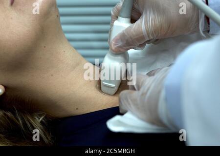 Endokriner Arzt, der einen Schilddrüsenultraschall bei einem Patienten aus der Nähe durchführt. Körperliche Untersuchung eines Patienten, endokrine Systemprobleme Stockfoto