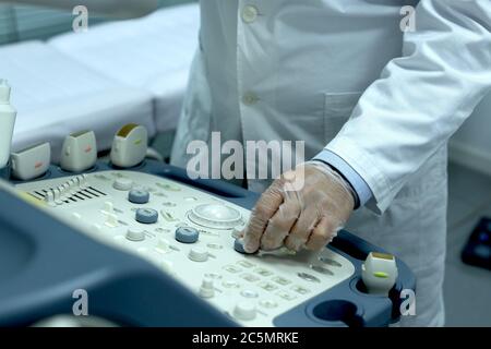 Nahaufnahme eines Arztes, der ein Gerät verwendet, um einen Patienten mit möglichen endokrinen Problemen zu sonden Stockfoto