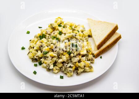 Ukrainischer und russischer Salat Olivier nach einem neuen Rezept auf einem weißen Teller. Gesunder Salat Olivier mit Fleisch, Mais und Scheiben Weißbrot. Delic Stockfoto