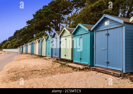 Strandhütten am Avon Beach bei Mudeford Christchurch mit blauem Himmel und Bäumen Stockfoto