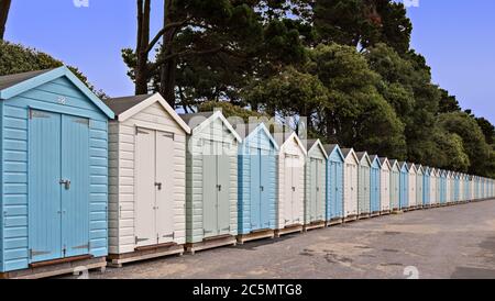 Strandhütten am Avon Beach bei Mudeford Christchurch mit blauem Himmel und Bäumen Stockfoto