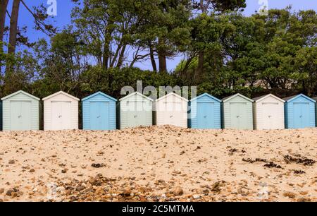 Strandhütten am Avon Beach bei Mudeford Christchurch mit blauem Himmel und Bäumen Stockfoto