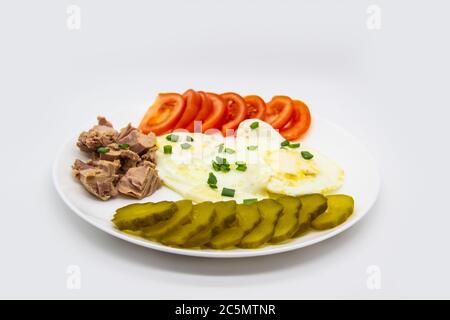 Köstlicher frischer Thunfisch mit Eiern, Tomaten, Gurken mit grünen Zwiebeln am Morgen. Gesundes und Diät-Frühstück mit Thunfisch, Eier und Gemüse auf der w Stockfoto