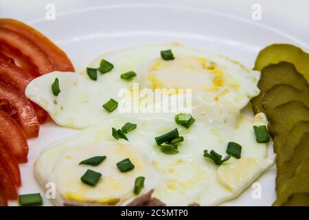 Köstlicher frischer Thunfisch mit Eiern, Tomaten, Gurken mit grünen Zwiebeln am Morgen. Gesundes und Diät-Frühstück mit Thunfisch, Eier und Gemüse auf der w Stockfoto