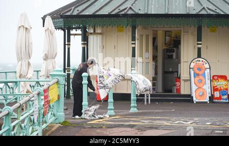 Brighton UK 4. Juli 2020 - Cafe-Mitarbeiter kämpfen sich darum, ihre Banner an einem nassen und windigen Tag in Brighton an der Südküste zu setzen : Credit Simon Dack / Alamy Live News Stockfoto